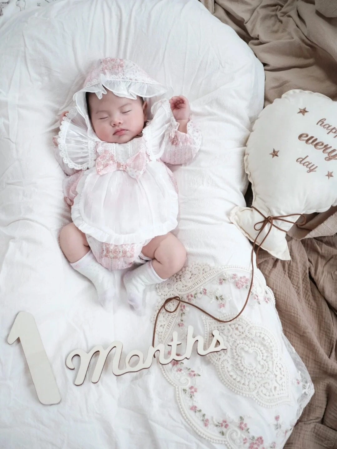 Em bé ngủ say trong bộ váy trắng ren, tạo dáng thiên thần nhỏ đáng yêu.