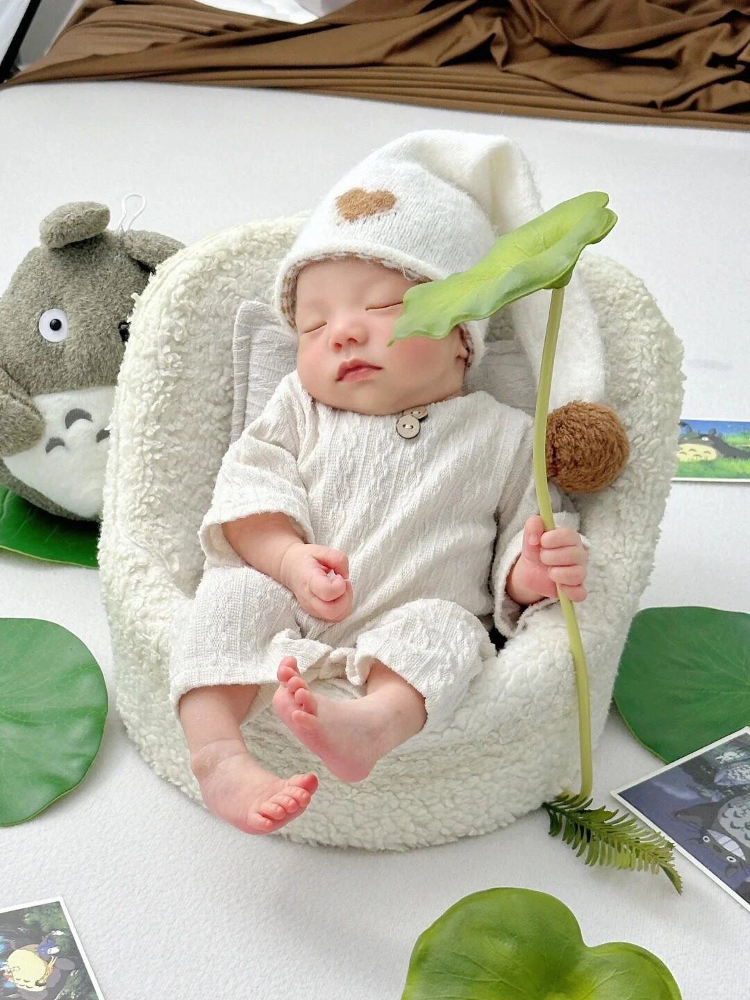 Thiên thần nhỏ đang ngủ say trong bộ trang phục len mềm mại tay cầm lá sen.