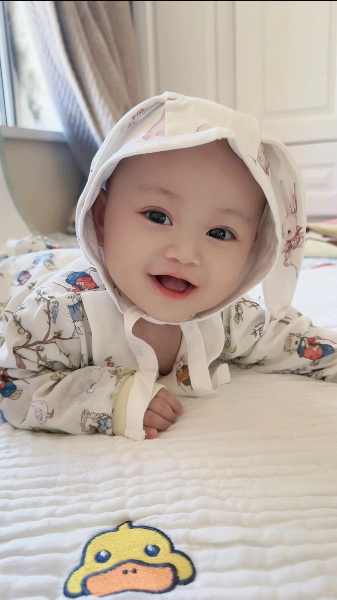 Nụ cười rạng rỡ, ánh mắt long lanh, bé nằm sấp đáng yêu vô cùng.