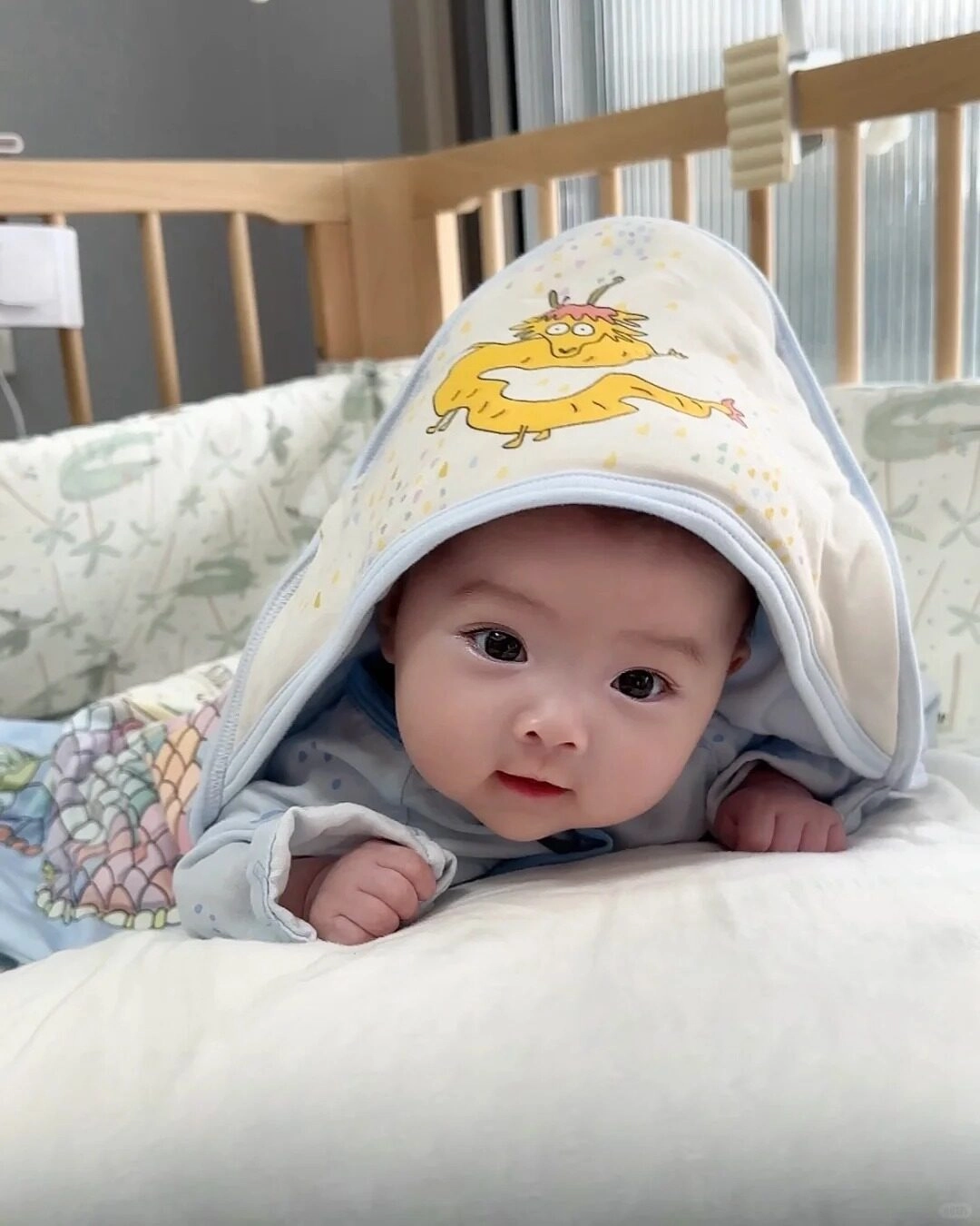 Em bé dễ thương tinh nghịch nằm úp trên nôi.