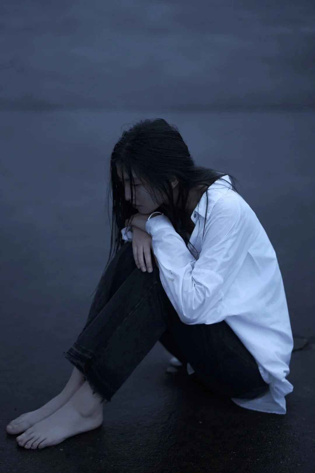 Cô gái trong chiếc áo sơ mi màu trắng gục đầu buồn bã bên đường.