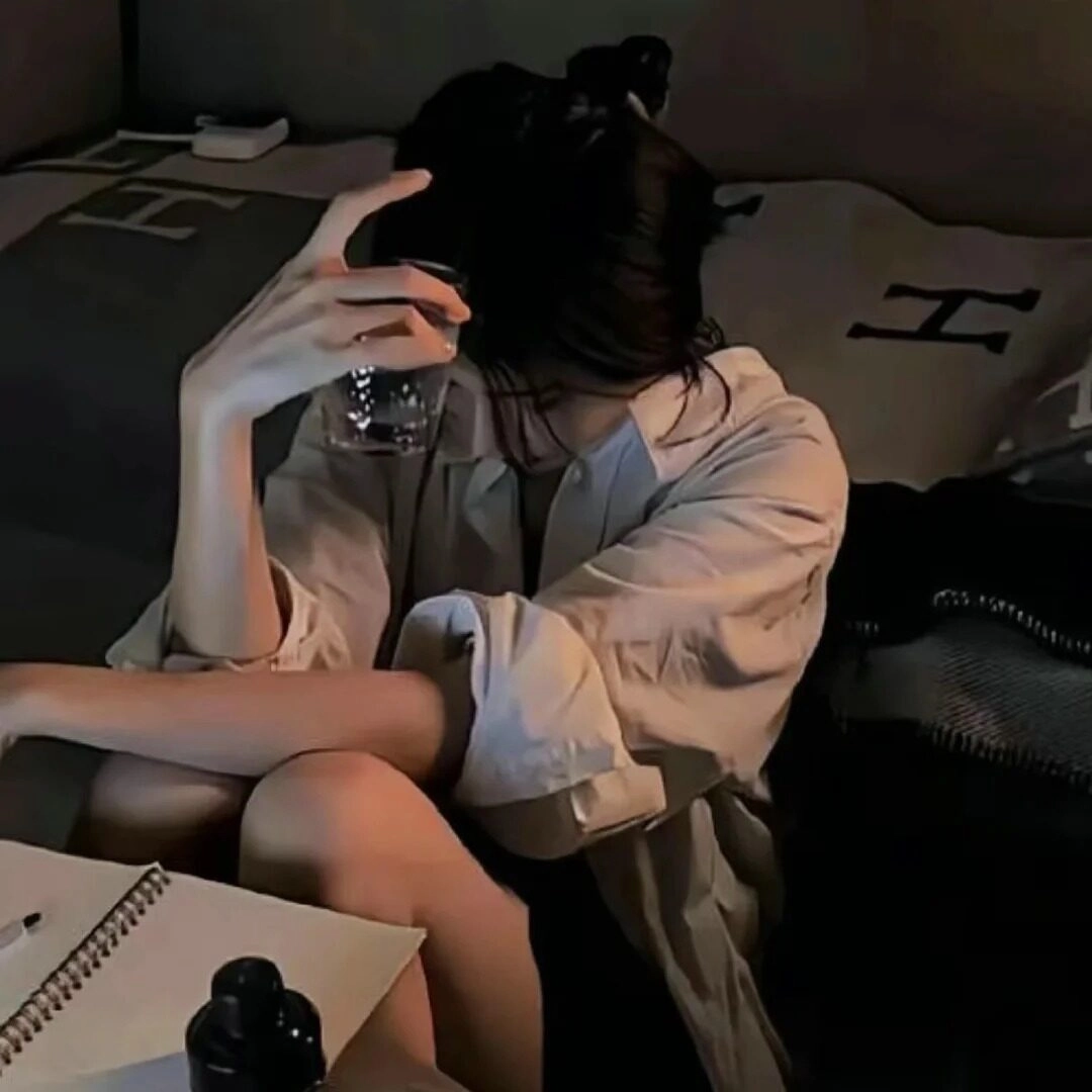 Cô gái ngồi trong góc phòng uống rượu để giải sầu.