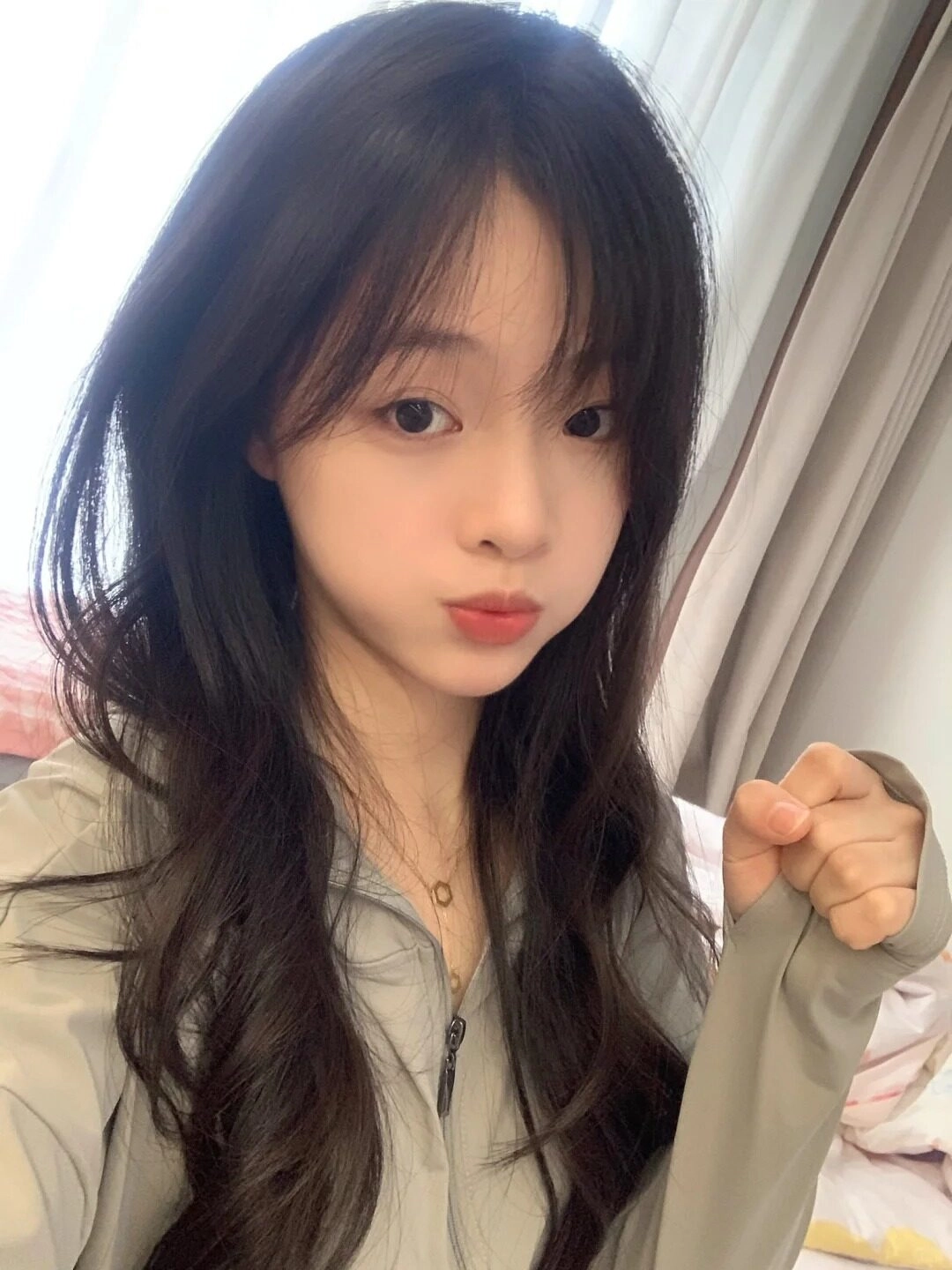 Mái tóc xoăn nhẹ buông tự nhiên, biểu cảm phồng má dễ thương và áo thể thao năng động.