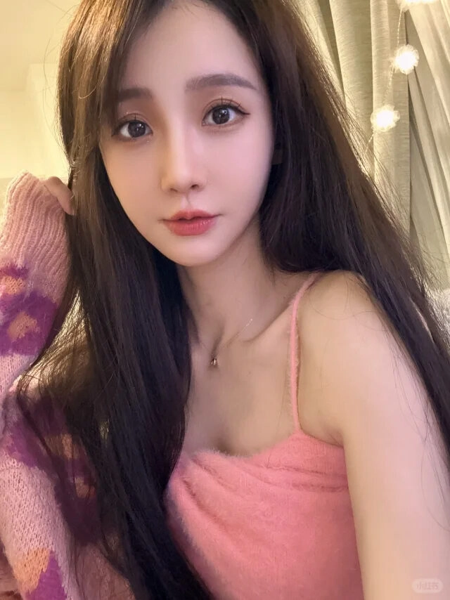 Áo hai dây hồng dịu dàng, suối tóc đen mềm mại, ánh mắt đầy cuốn hút.