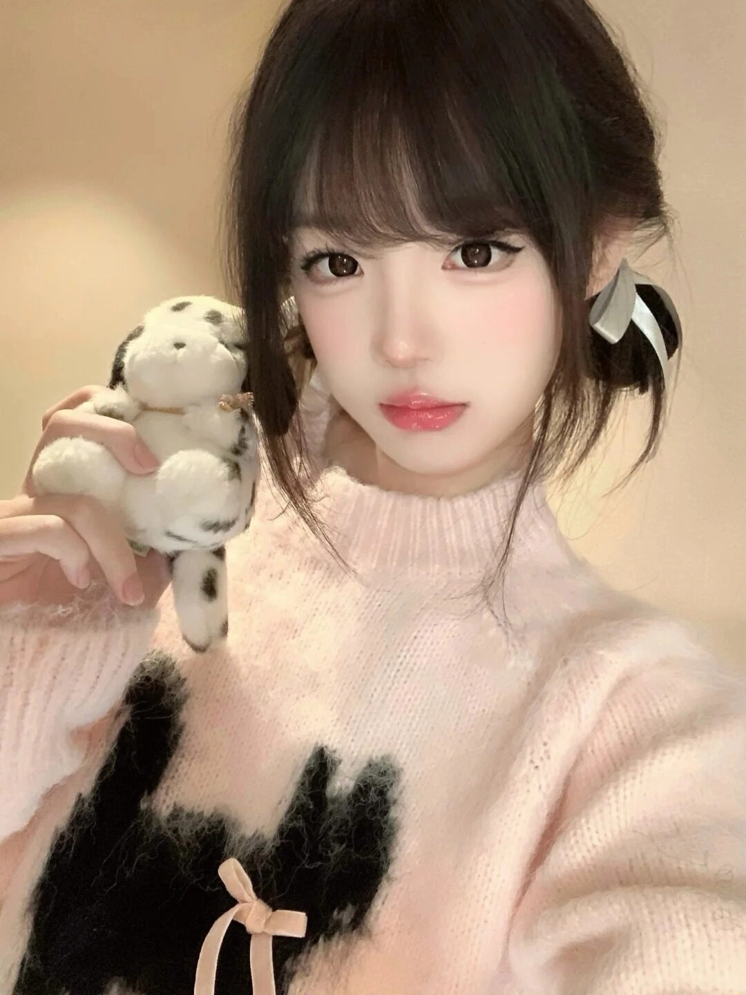 Mái tóc buộc hai bên đáng yêu, áo len hồng phối nơ mang lại vẻ ngọt ngào.