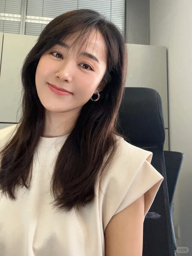 Nụ cười rạng rỡ, tóc xoăn tự nhiên, phong cách văn phòng trang nhã.