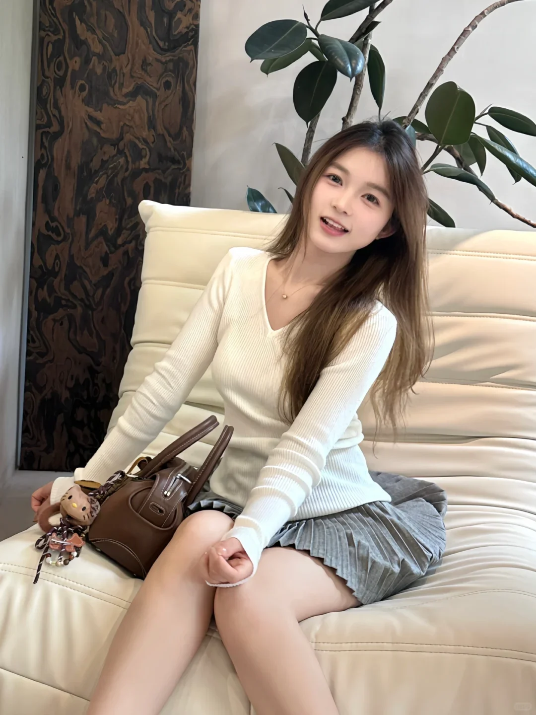 Áo len trắng nhẹ nhàng phối chân váy xếp ly, tạo nét thanh lịch cuốn hút.