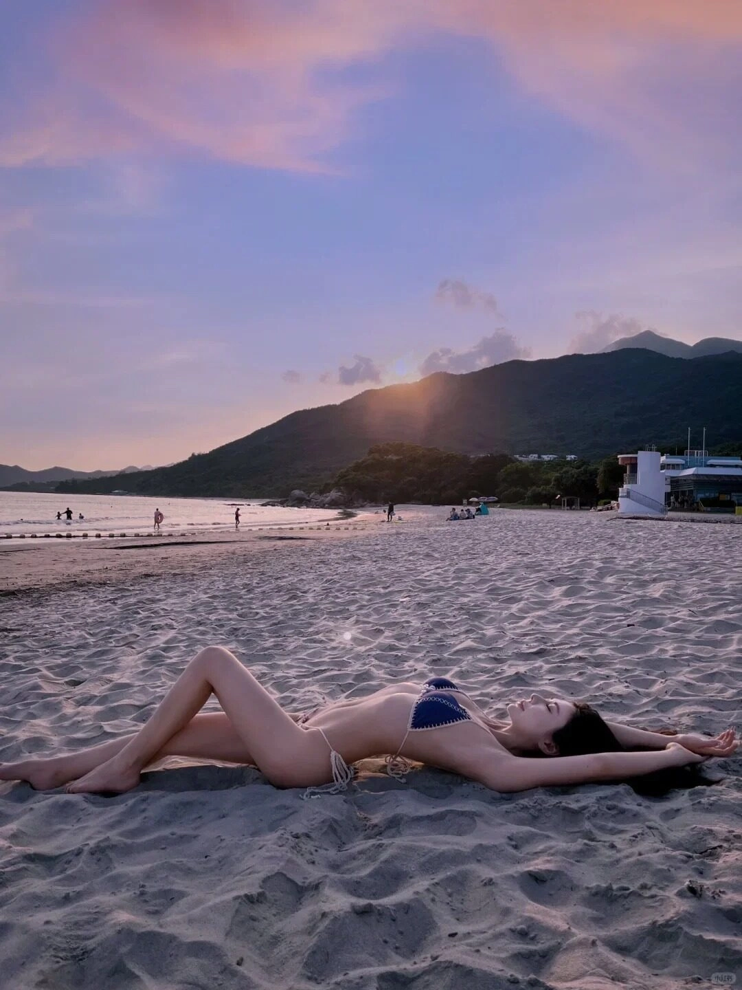 Bộ áo tắm đen quyến rũ cô nàng nằm tựa lưng vào bờ cát trắng.