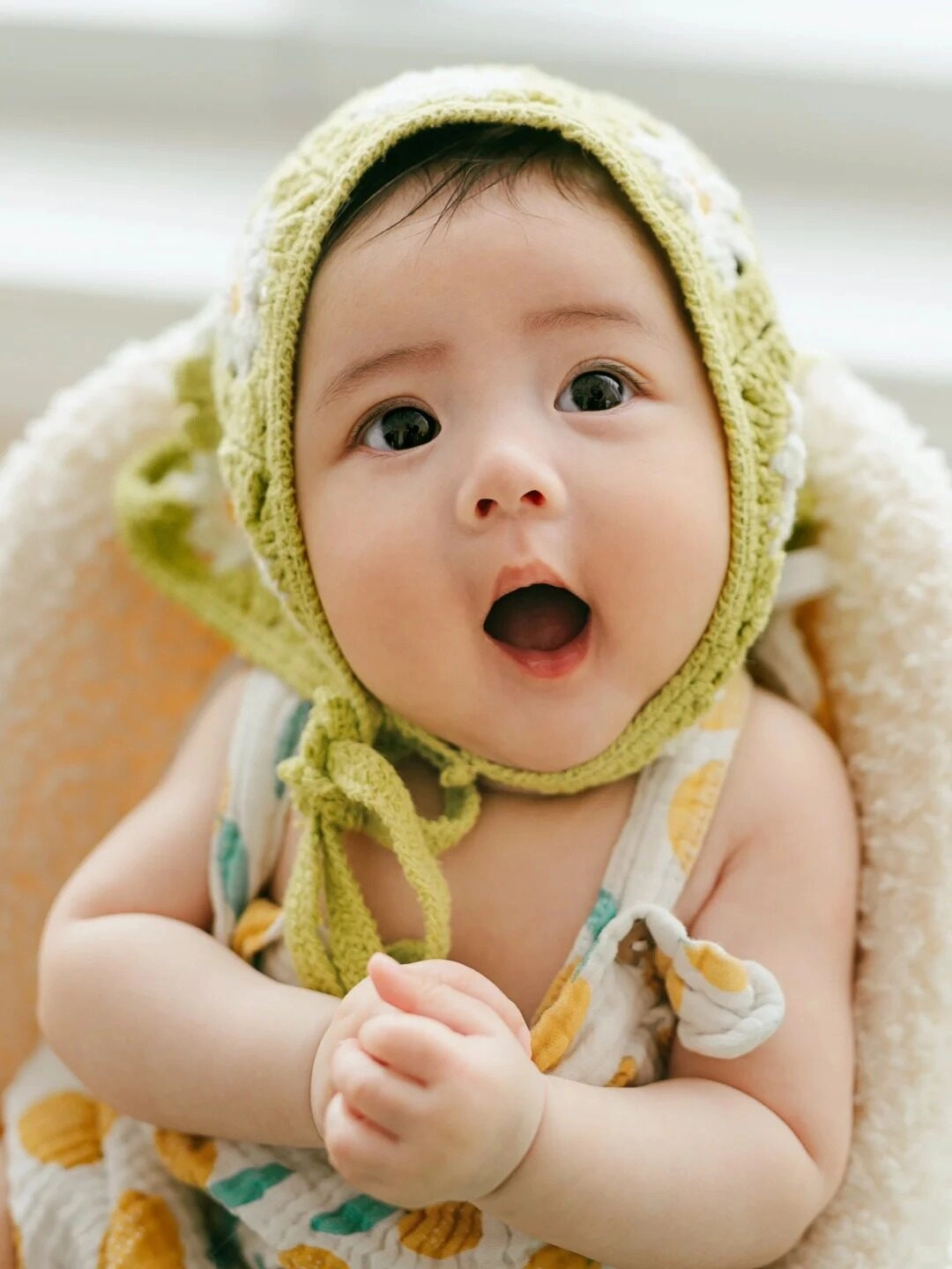 Bé đội mũ len xanh, mắt to tròn đầy hứng khởi, tay chắp như đang cầu nguyện.