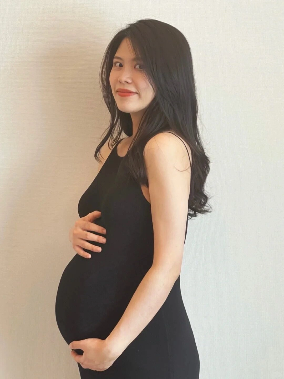 Váy bầu đen đơn giản, mẹ nhẹ nhàng đặt tay lên bụng, ánh mắt rạng rỡ.