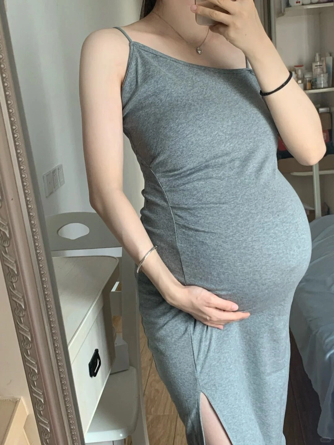 Chiếc váy ôm sát màu xám với đường xẻ cao, tôn lên đường cong mẹ bầu.