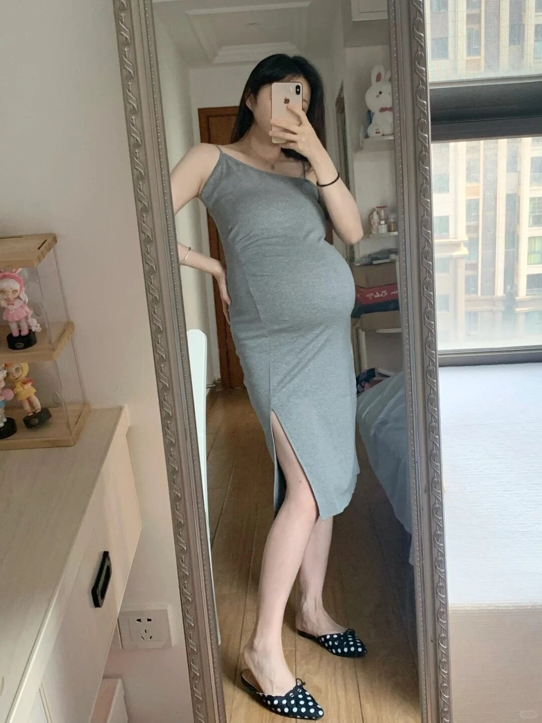 Gương phản chiếu hình ảnh mẹ bầu trong chiếc váy xám lệch vai, dịu dàng đầy nữ tính.