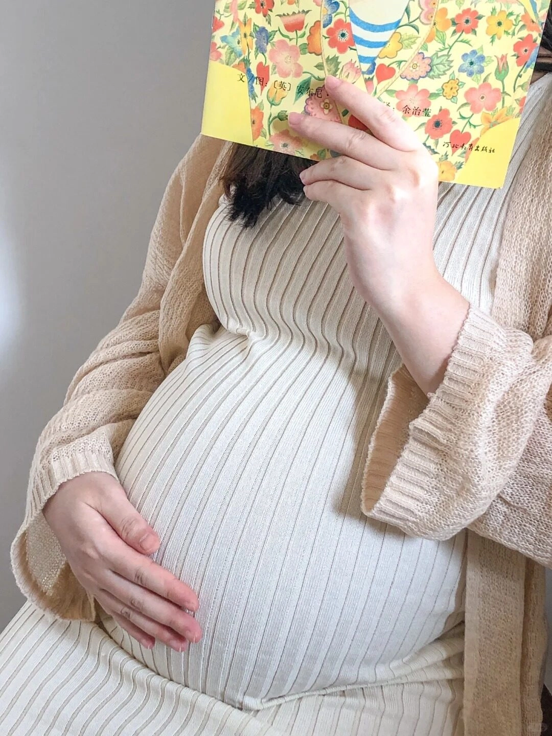Bầu ấm trong váy len gân màu kem, tay khẽ đặt lên bụng đầy yêu thương. 