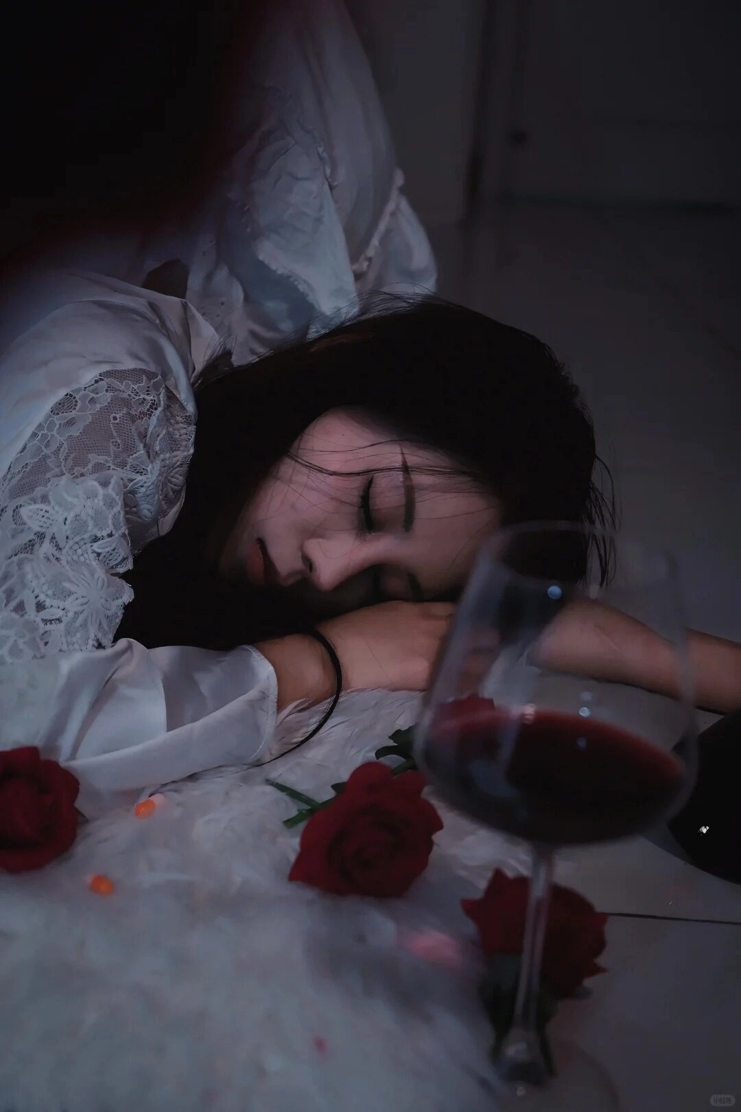 Bên ly rượu đỏ và những cánh hồng rơi rụng, cô gái chìm trong cơn say buồn bã.