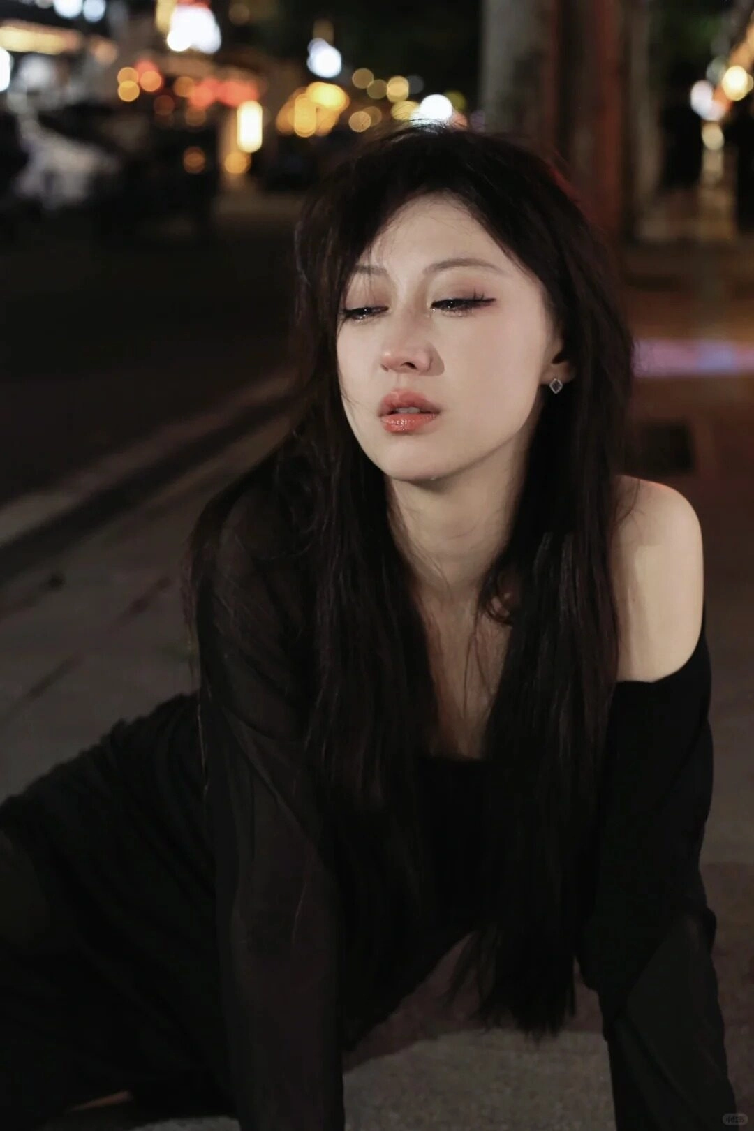 Cô gái trong chiếc váy đen lặng lẽ nhìn về phía xa, mắt nhuốm buồn.