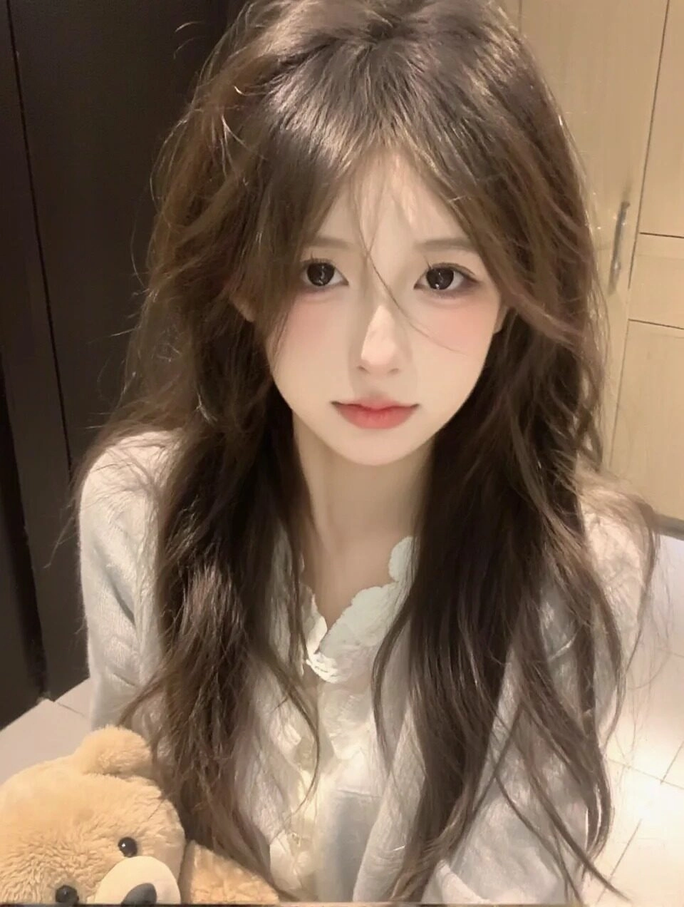 Tóc xoăn nhẹ buông xõa đầy lãng mạn, ánh mắt cuốn hút cùng gấu bông đáng yêu.