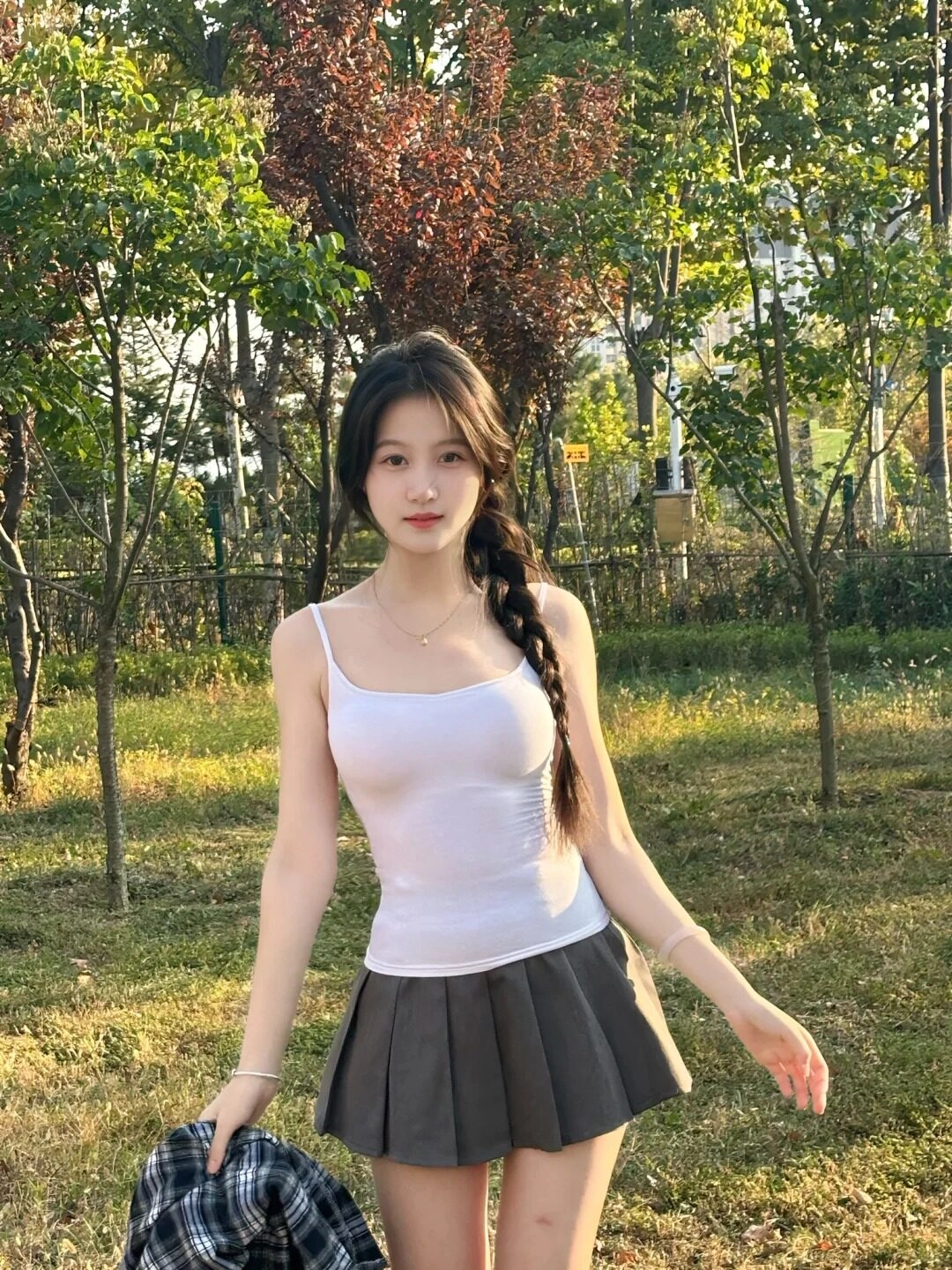 Thả áo khoác, tóc tết nhẹ nhàng, dáng đứng tự tin giữa nắng chiều.