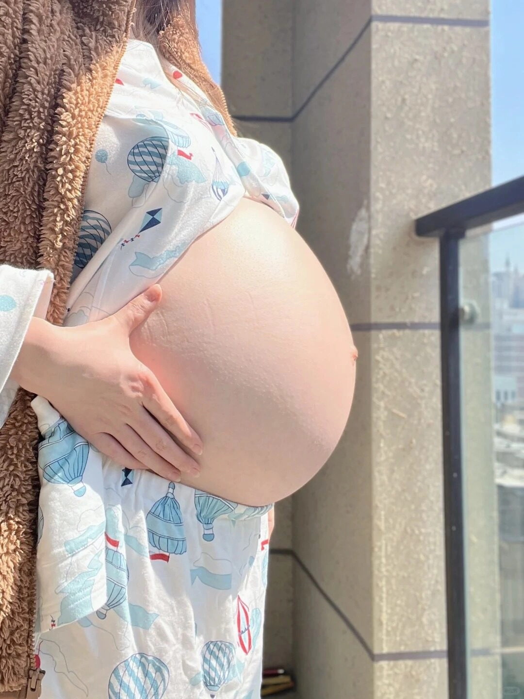 Hình ảnh bụng bầu 9 tháng trong bộ đồ bầu rộng của bà mẹ đang đứng phơi nắng.