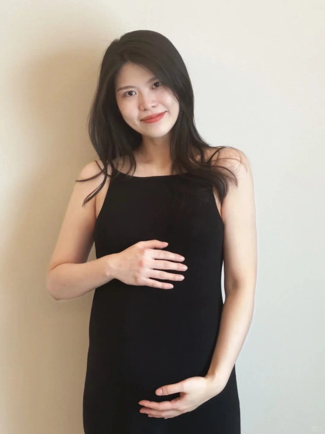 Diện váy đen hai dây, cô gái nở nụ cười rạng rỡ, tay ôm lấy bụng bầu.! 