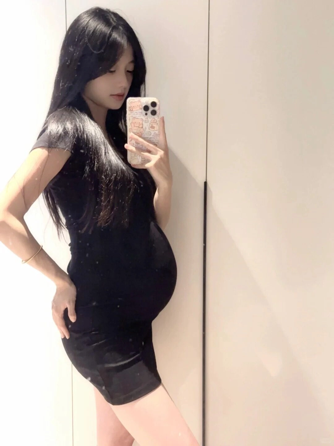 Váy đen ngắn năng động, cô gái soi gương, bàn tay đặt nhẹ lên mông.