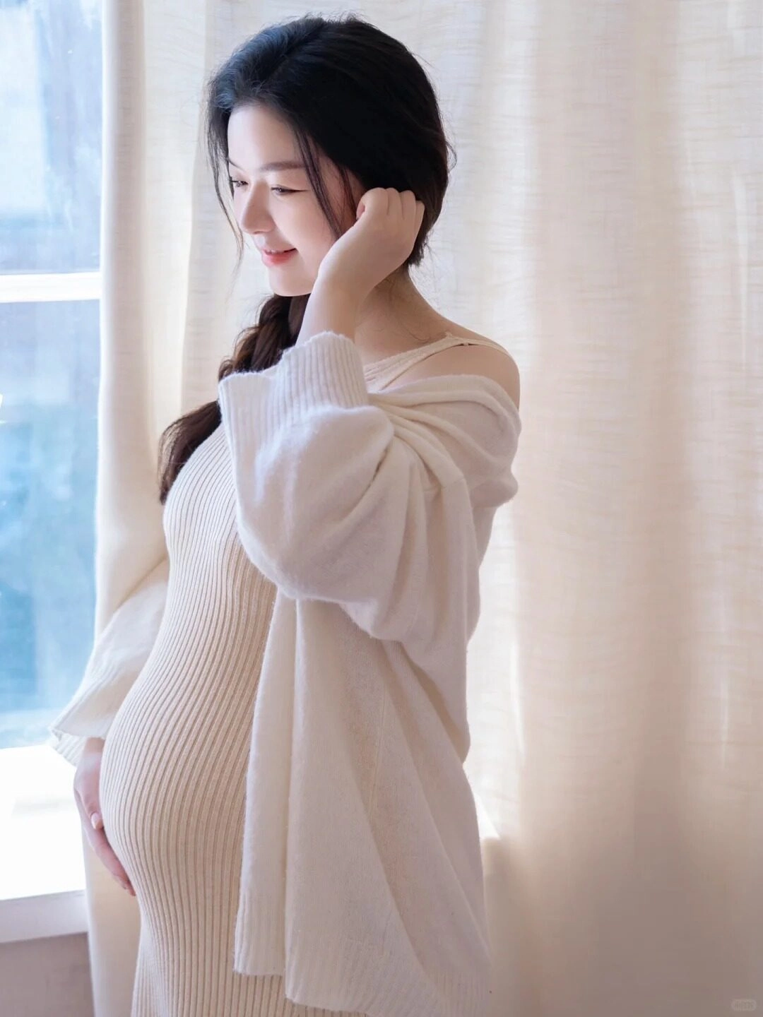 Váy len trắng kết hợp cardigan rộng, mẹ bầu khẽ mỉm cười trong ánh nắng nhẹ.