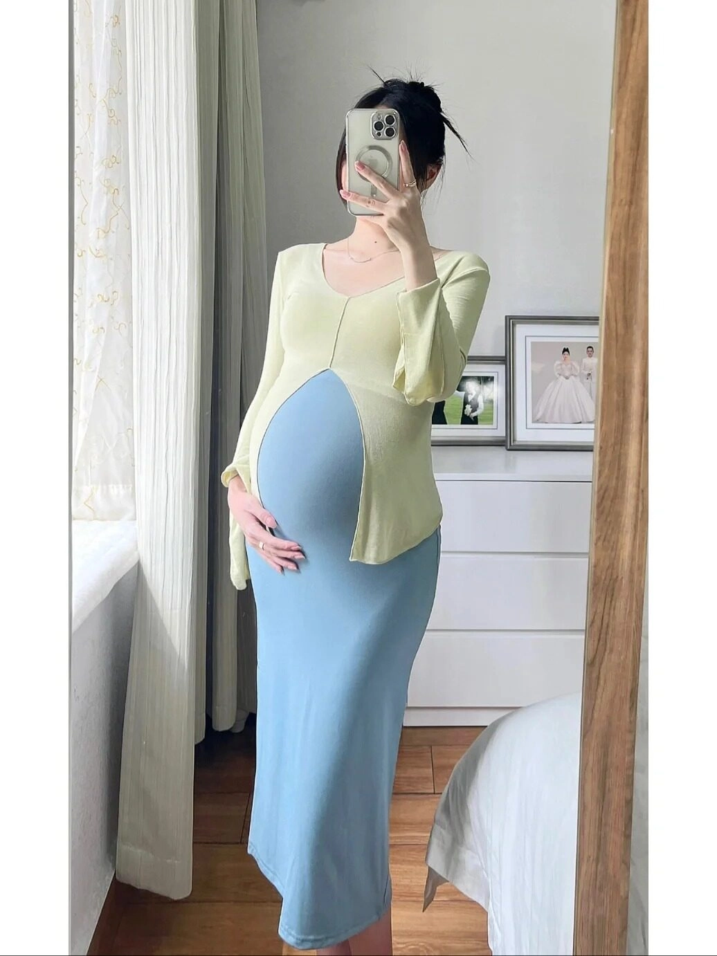 Set váy ôm xanh pastel phối áo len vàng, mẹ bầu tạo dáng sang trọng trước gương.