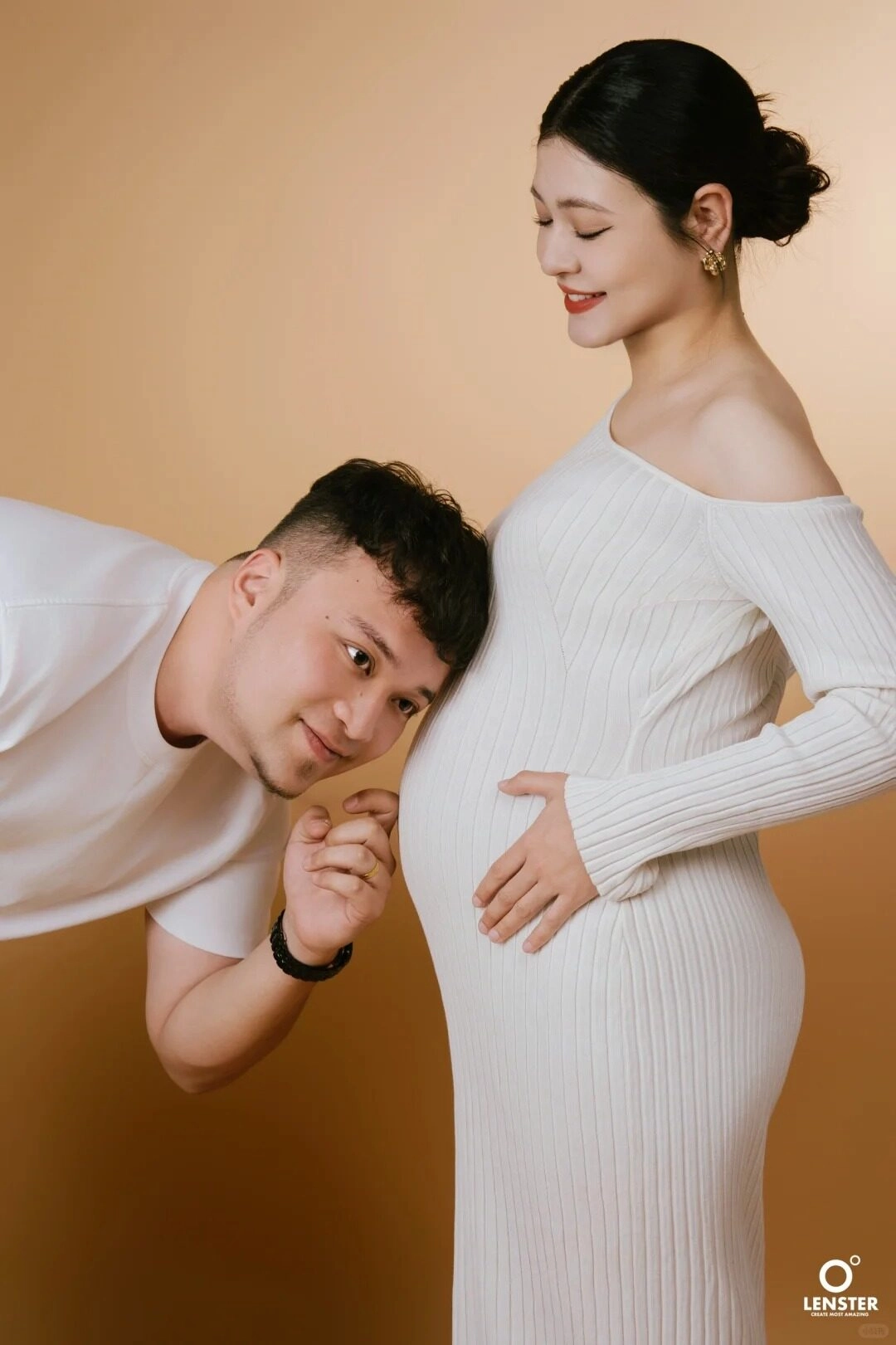 Mẹ diện váy len trắng trễ vai, hạnh phúc bên bố, lắng nghe con yêu.