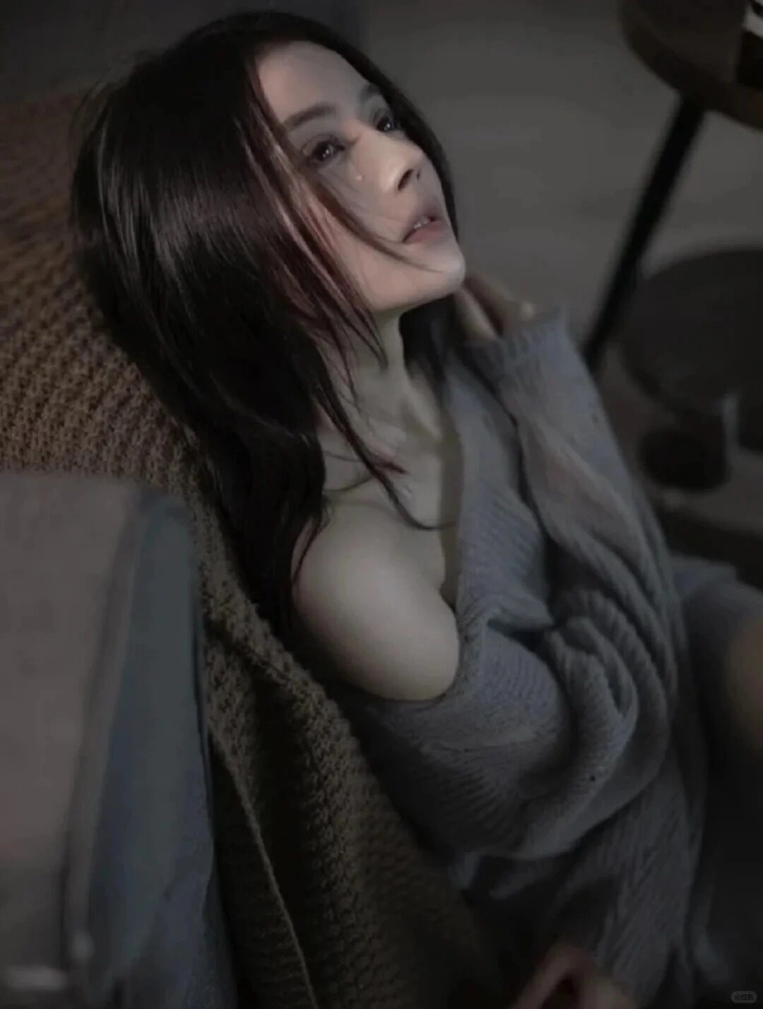 Chiếc áo len xám trễ vai, cô gái ngồi bệt xuống sàn, ánh mắt vô hồn.