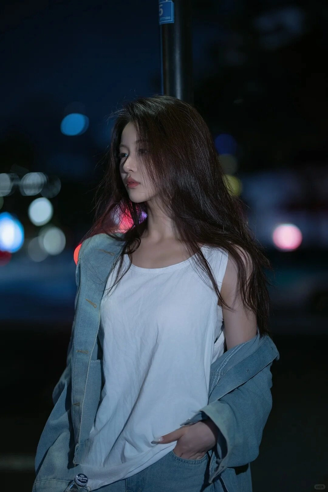 Cô gái trong chiếc áo blazer rộng, tựa vào lan can, ngước lên thinh lặng giữa ánh đèn đường.