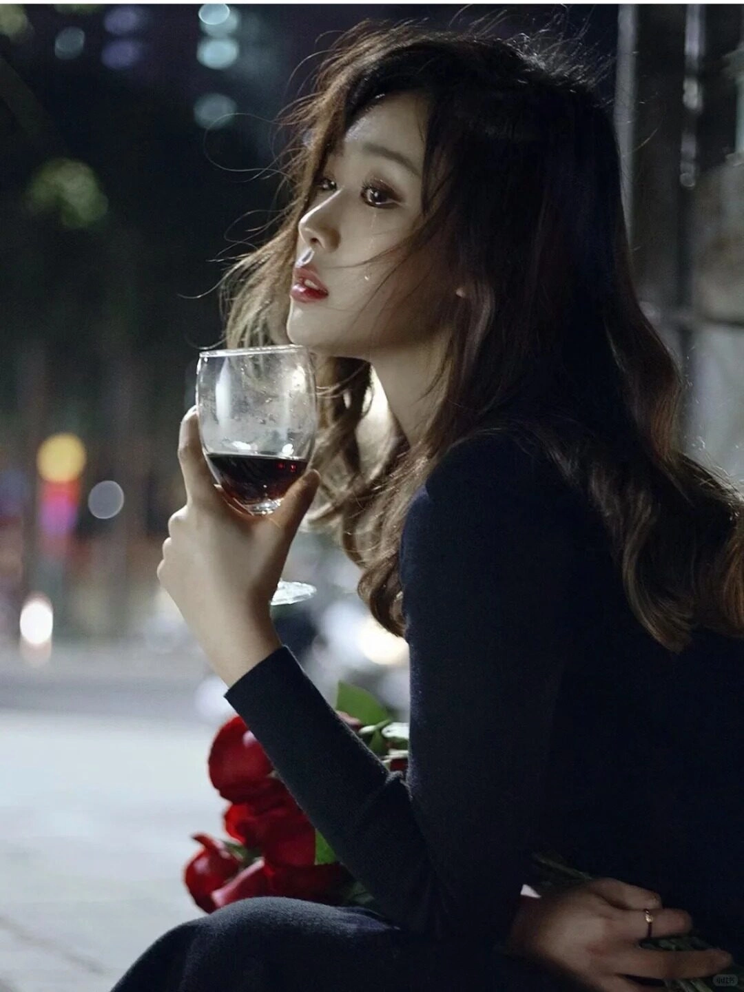 Ly rượu đỏ trong tay, đôi mắt buồn lặng lẽ giữa đêm phố thị.