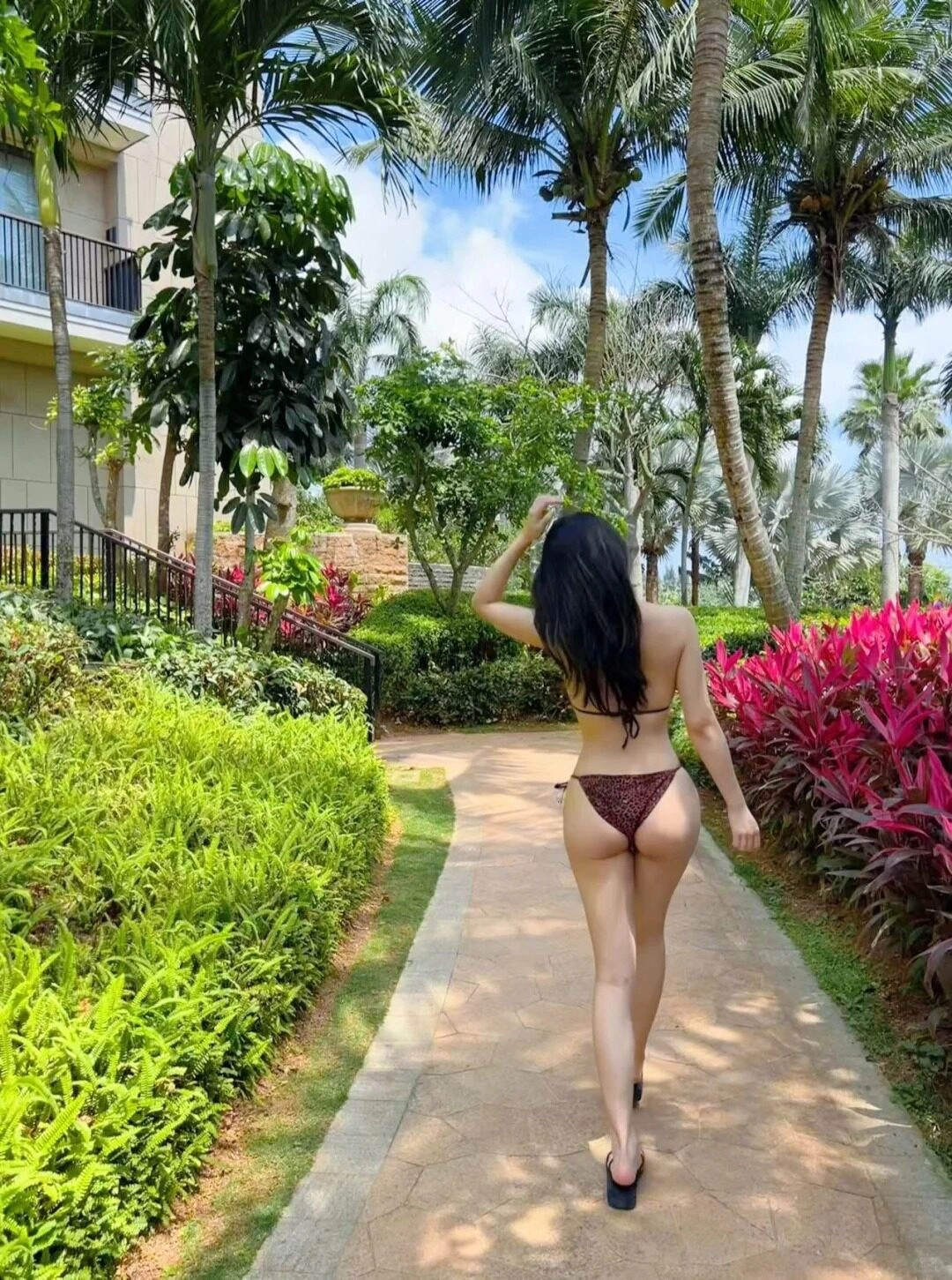 Mặc bikini đi bộ trong khuôn viên của resort xanh tươi và mát mẻ