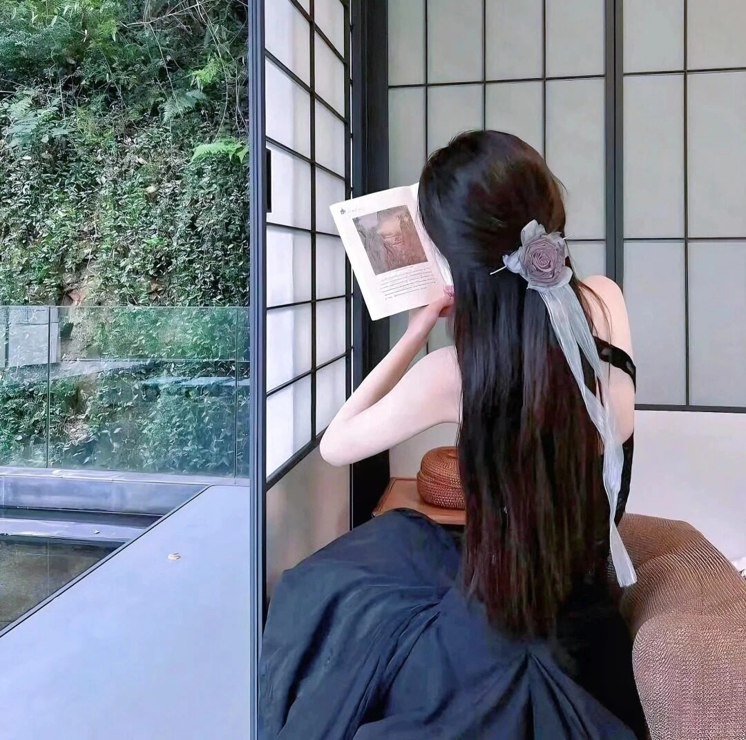 Thiếu nữ váy đen thanh lịch, cài hoa tóc, đọc sách cạnh cửa sổ dịu dàng.