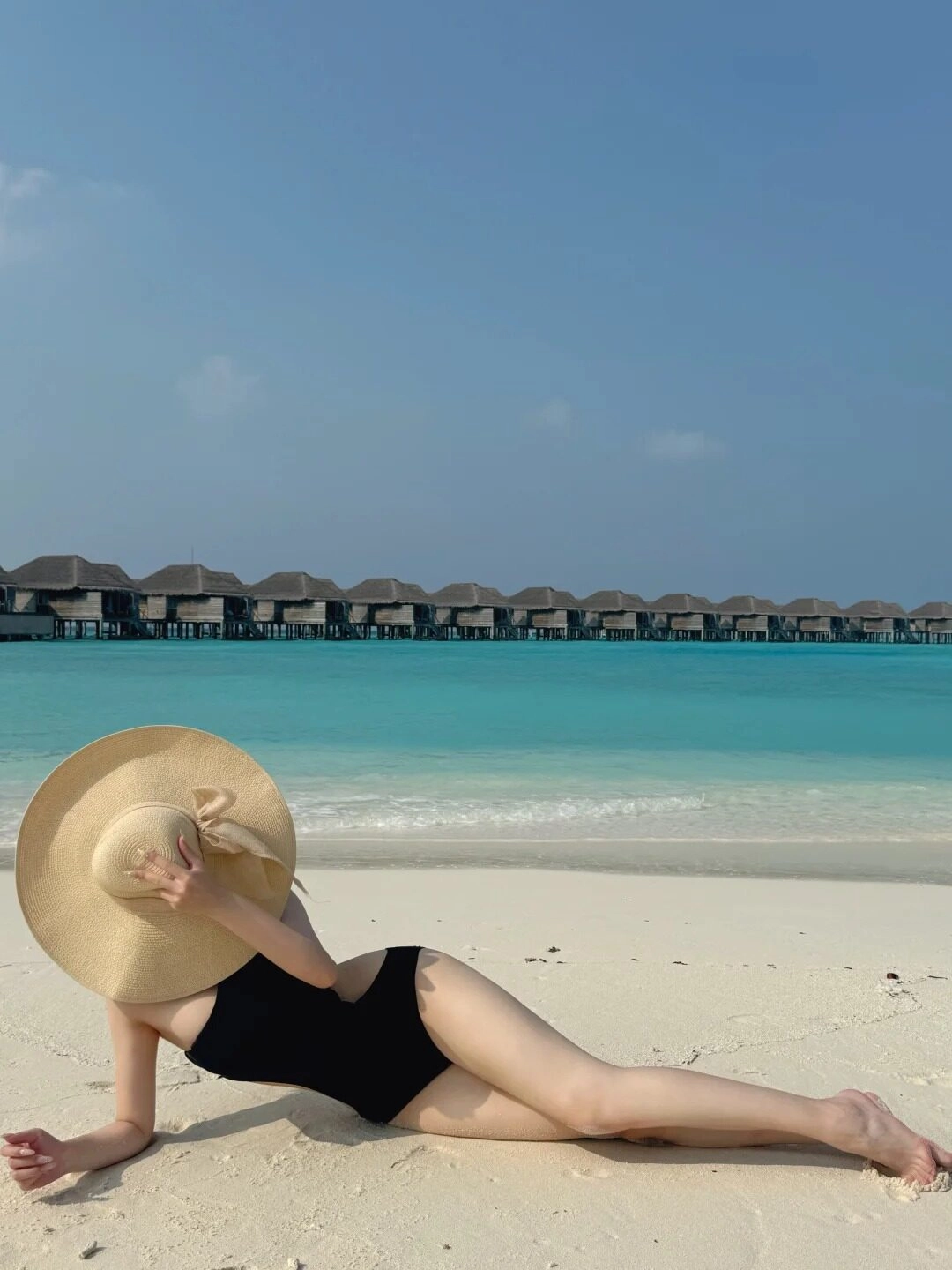 Nằm thư giãn trên bãi biển, mũ rộng vành che nắng dịu dàng.