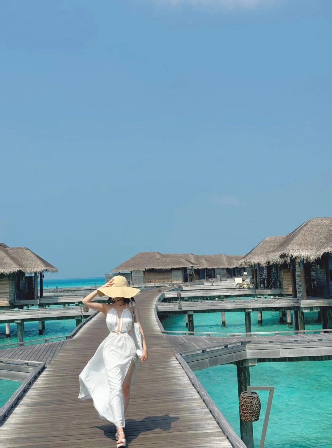 Dáng nàng thư tắm tha trên cầu gỗ, Váy trắng và mũ rộng vành bay theo gió