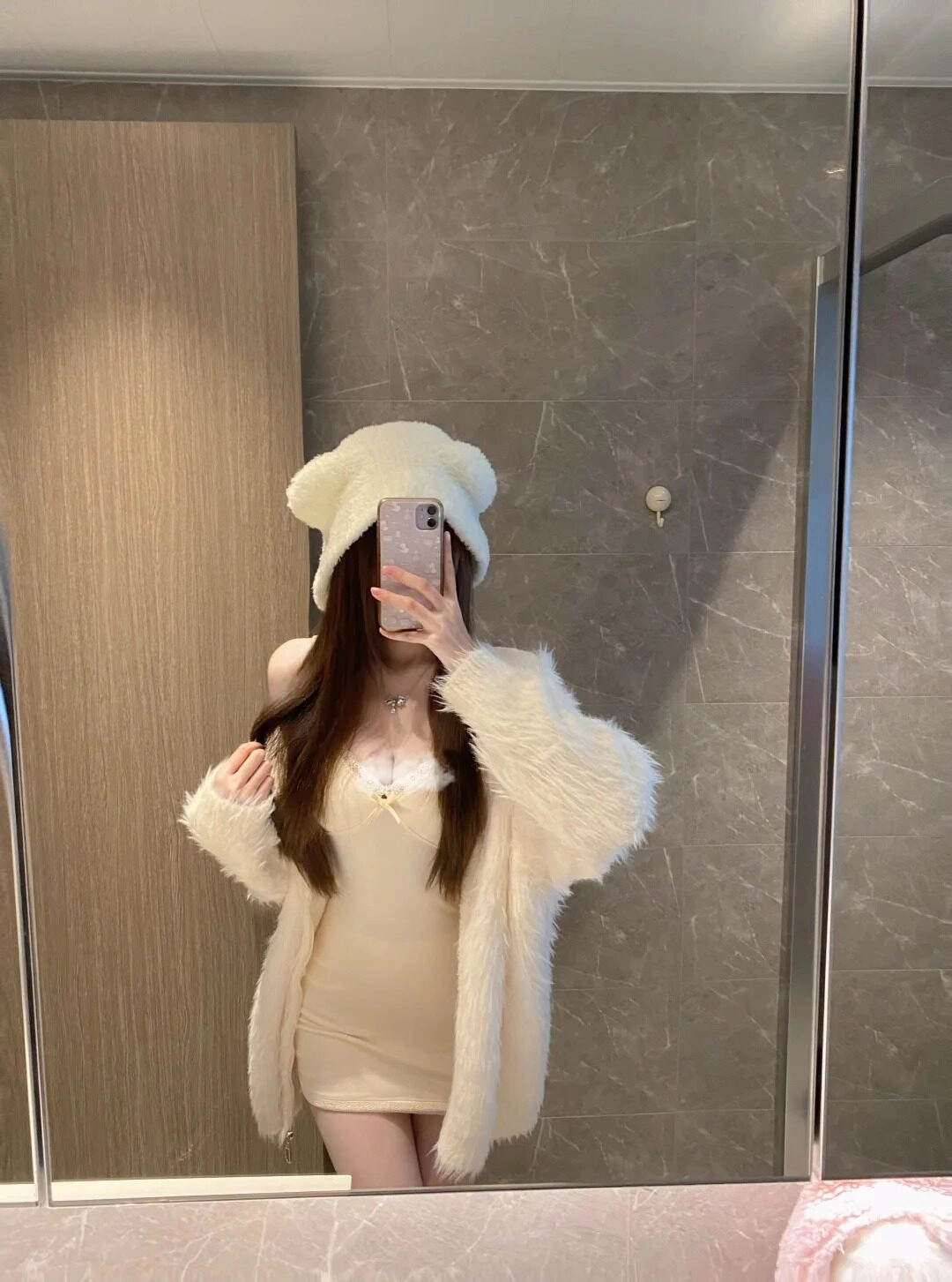 Đội mũ gấu dễ thương, trang phục ấm áp nhẹ nhàng, tạo dáng trước gương.