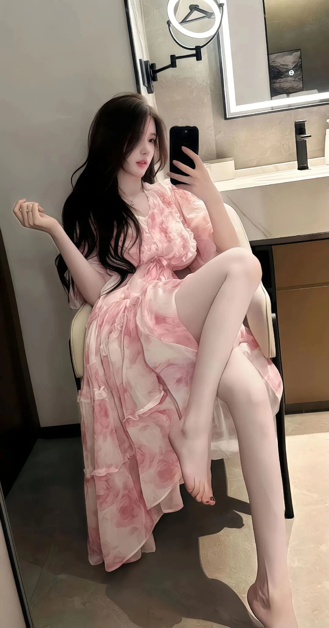 Váy hoa nhẹ nhàng, dáng ngồi thoải mái trước gương, tạo nét nữ tính.