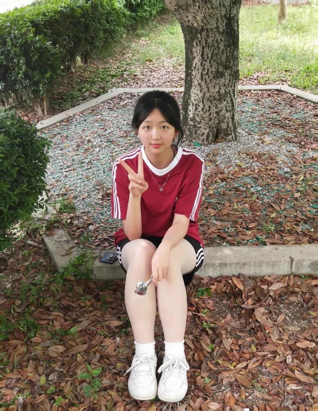 Cô bé 2k9 xinh xắn với áo đỏ thể thao, nụ cười tươi Viền và kiểu tóc đơn giản.