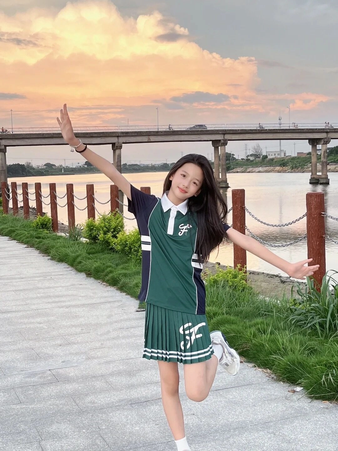 Cô gái nhỏ tự tin tạo dáng bên sông lúc hoàng hôn.