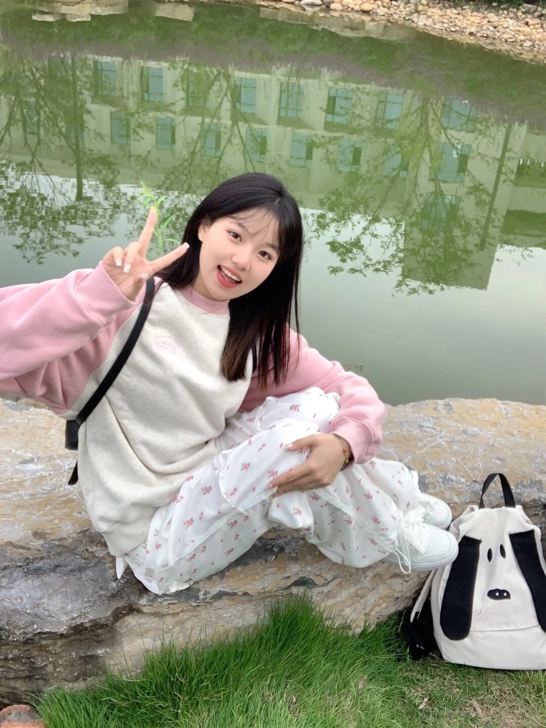 Cô gái nhỏ nhắn vui vẻ tạo dáng đáng yêu bên hồ nước xanh.