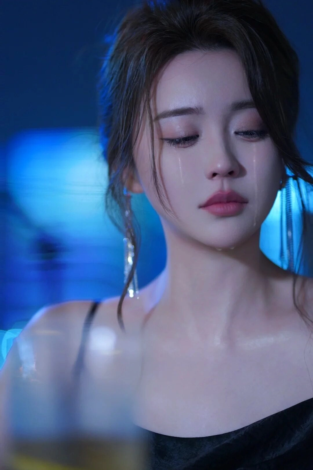 Đôi mắt nhòe lệ dưới ánh đèn xanh, lặng thinh trong nỗi đau.