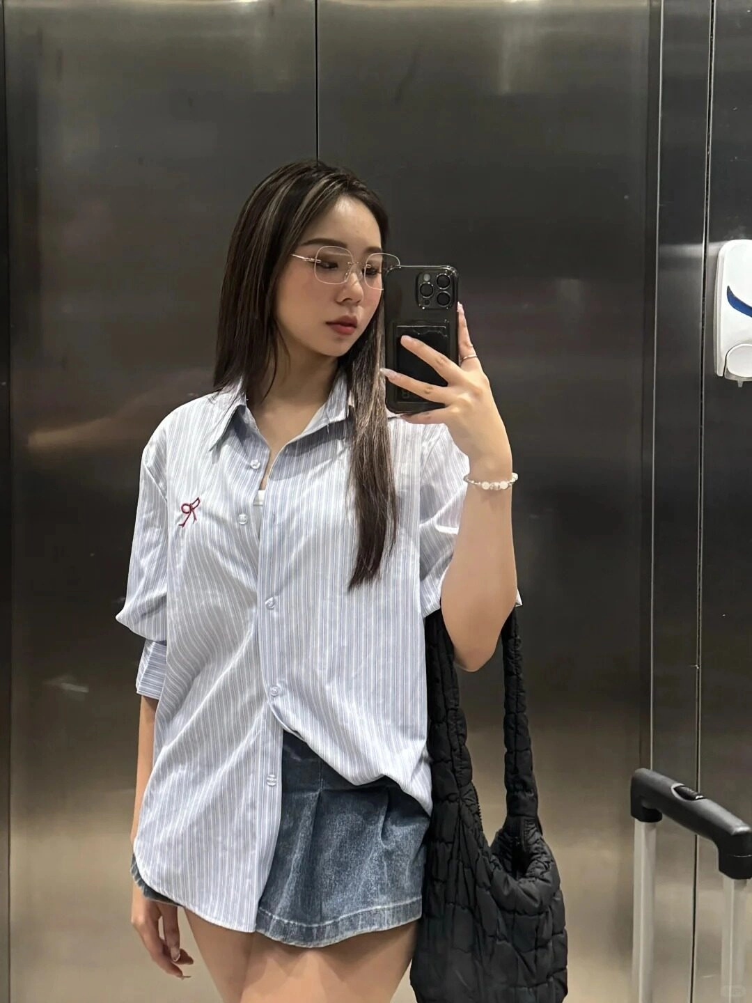 Áo sơ mi xanh ngọc, váy chân váy jean, đeo kính, tóc dài thẳng tự nhiên.