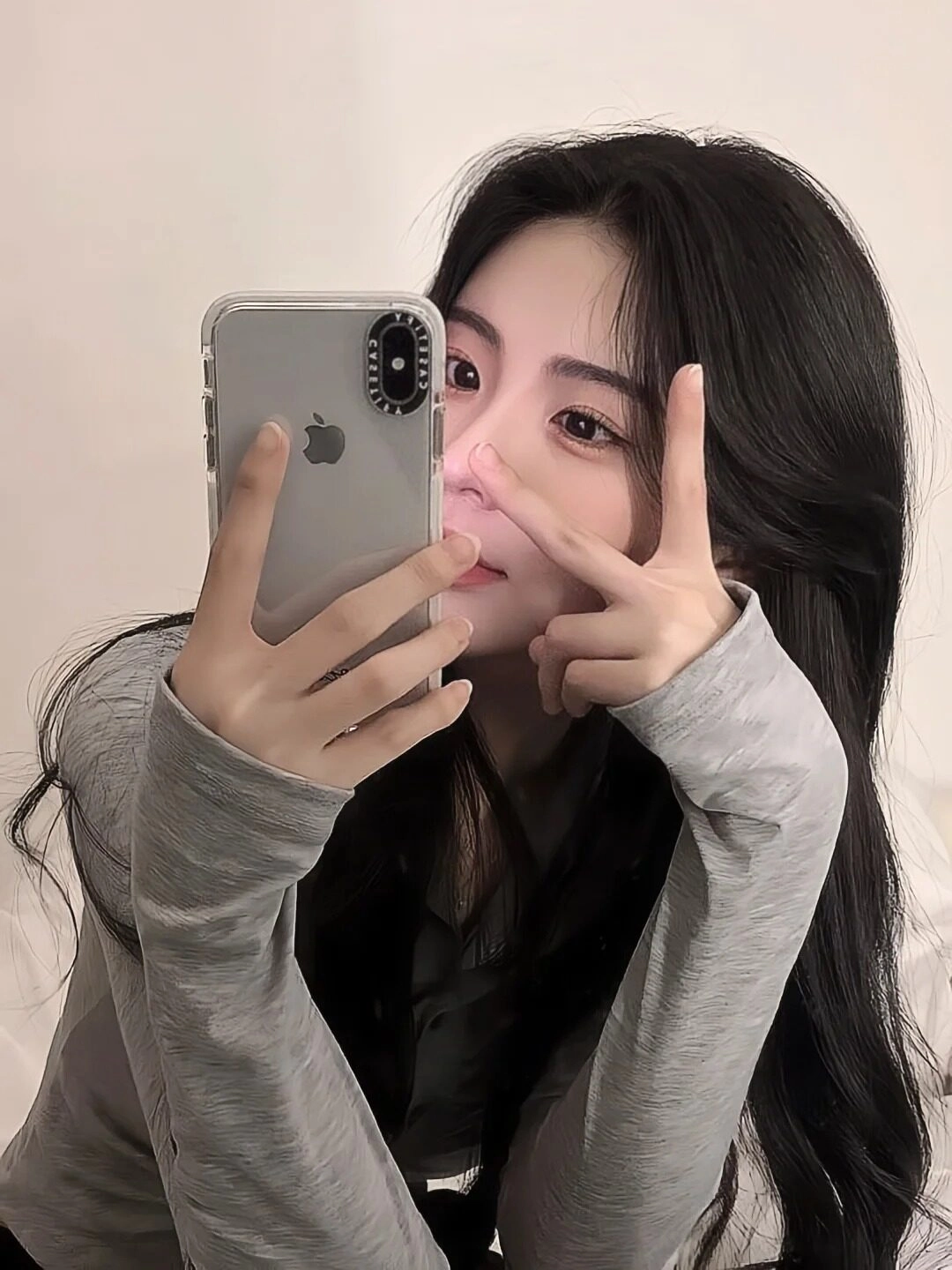 Tóc xoăn nhẹ, tay tạo kiểu chữ V dễ thương, ánh mắt vui vẻ selfie.