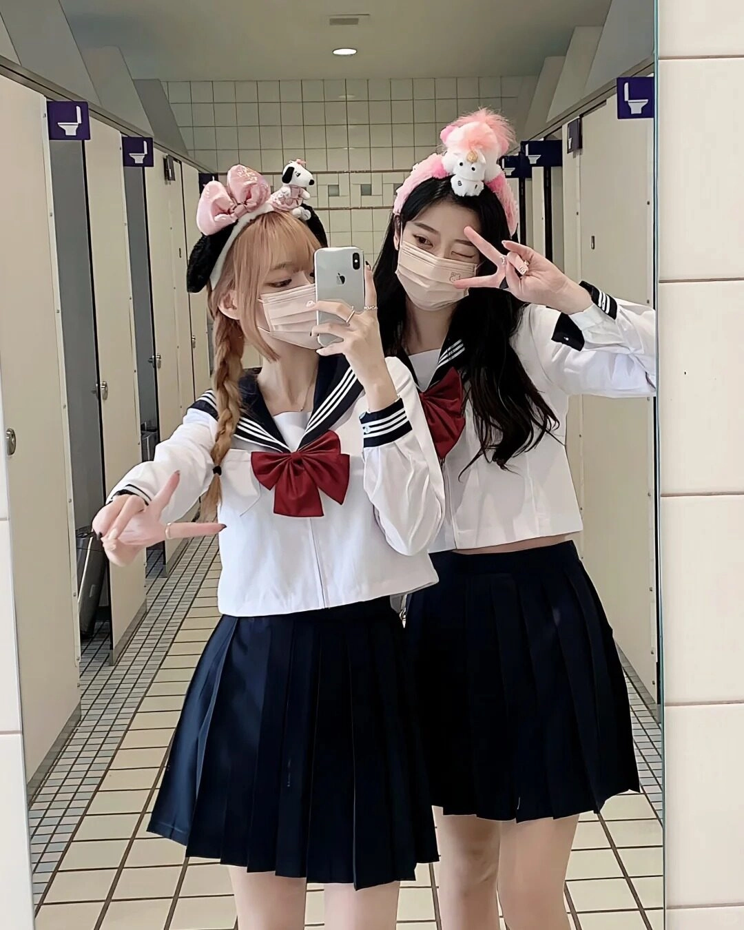 Đồng phục nữ sinh đáng yêu, đeo khẩu trang, tạo kiểu dáng vui vẻ trước kính.