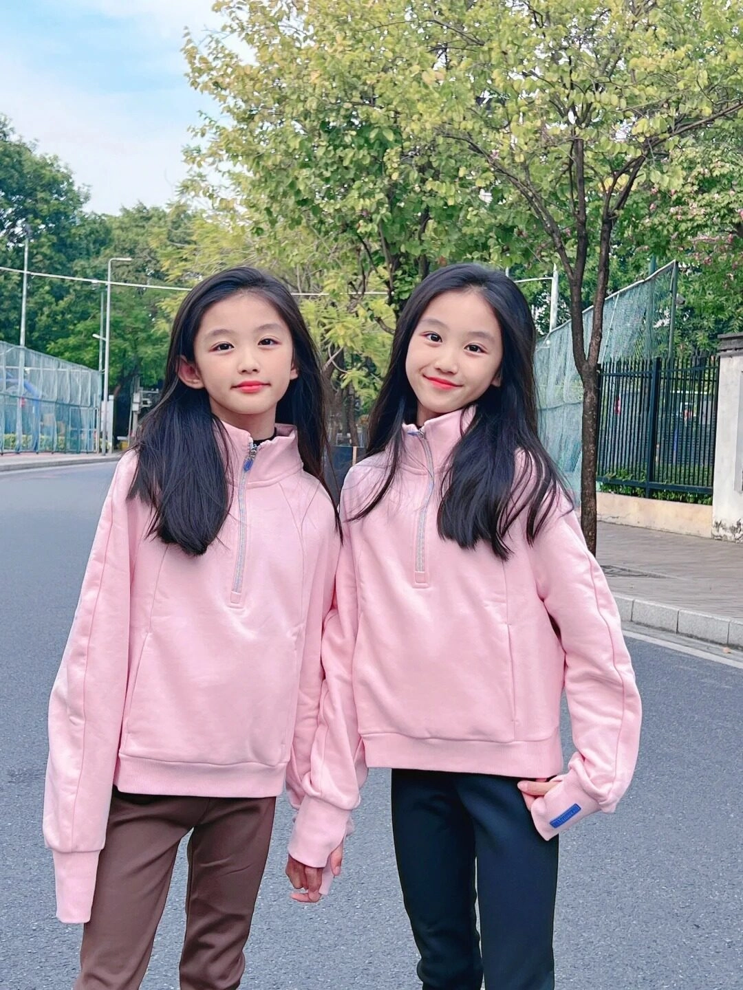 Hai cô gái xinh xắn diện áo hồng, dạo phố với nụ cười đáng yêu.