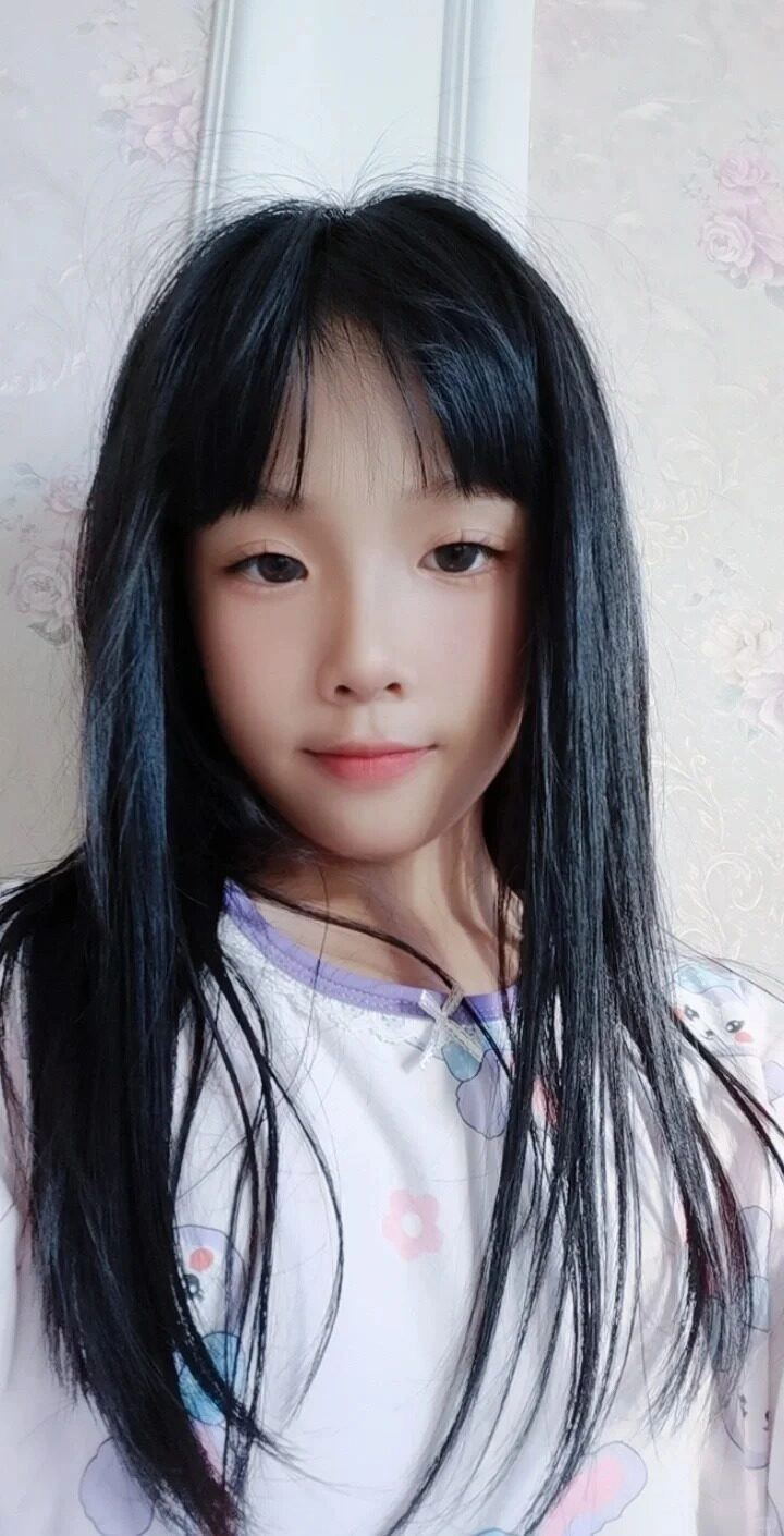 Bé gái mái tóc đen mượt, ánh mắt dịu dàng nhìn thẳng vào ống kính.