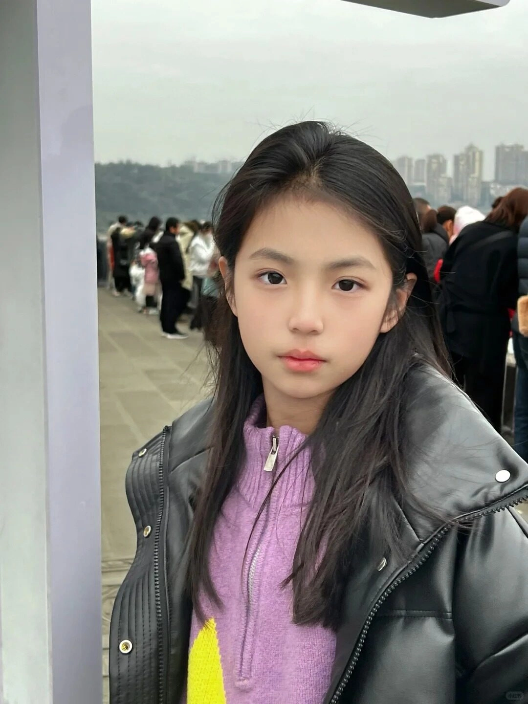 Cô bé với áo len tím nhẹ nhàng, ánh mắt thu hút giữa đám đông.