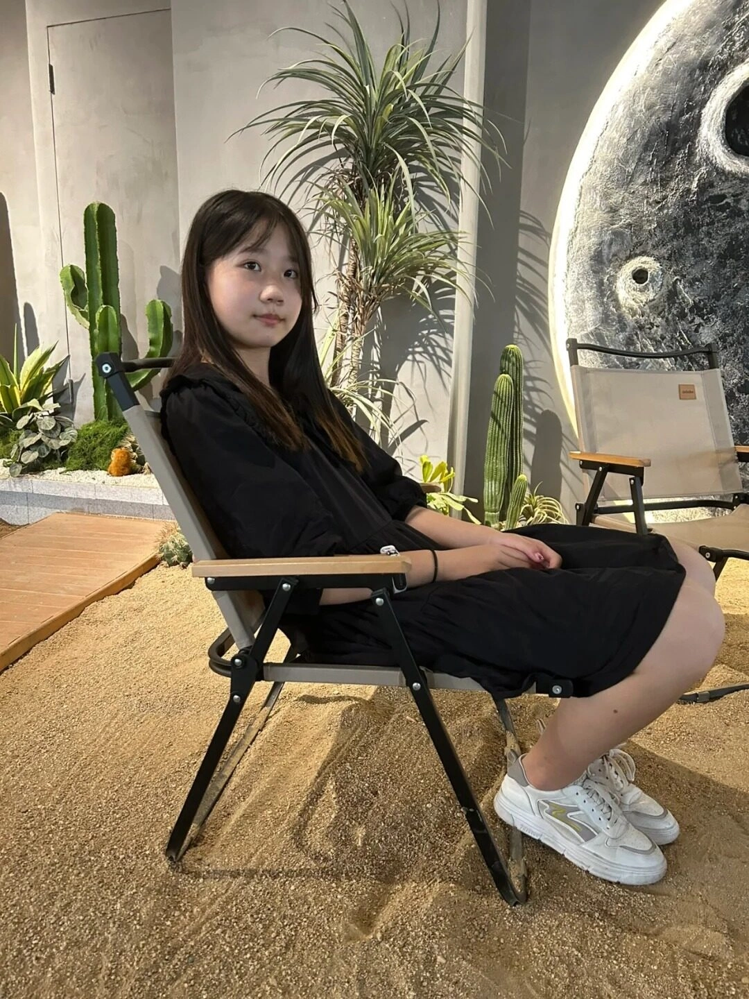 Cô gái ngồi thư giãn trên ghế, tận hưởng không gian nhẹ nhàng, ấm áp.