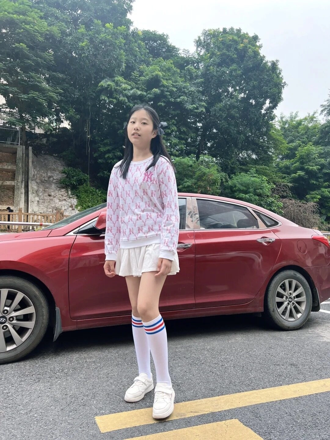 Em gái tạo dang chụp hình bên cạnh ô tô đỏ