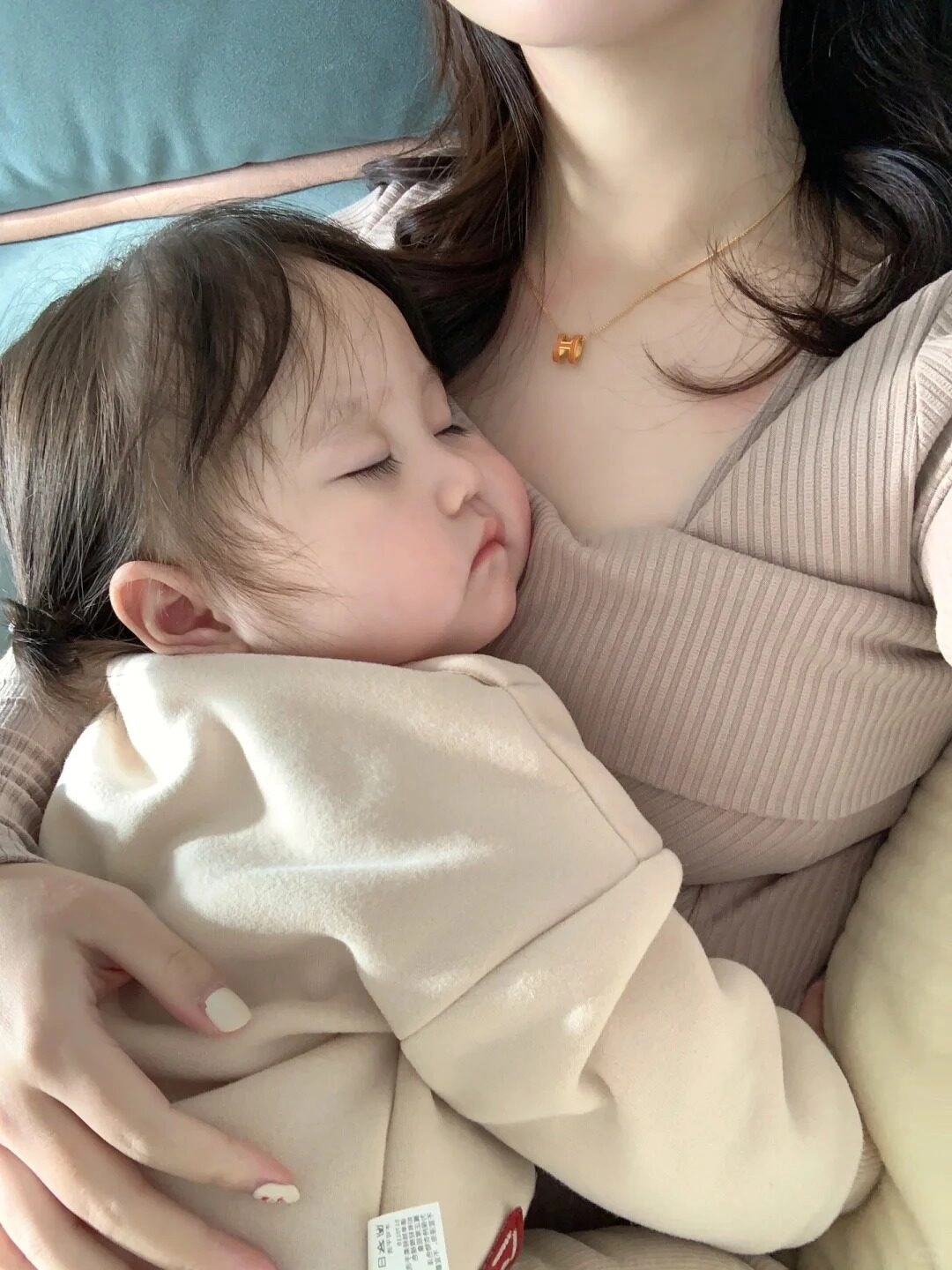 Em bé ngủ yên bình trong vòng tay mẹ, tạo cảm giác an lành.
