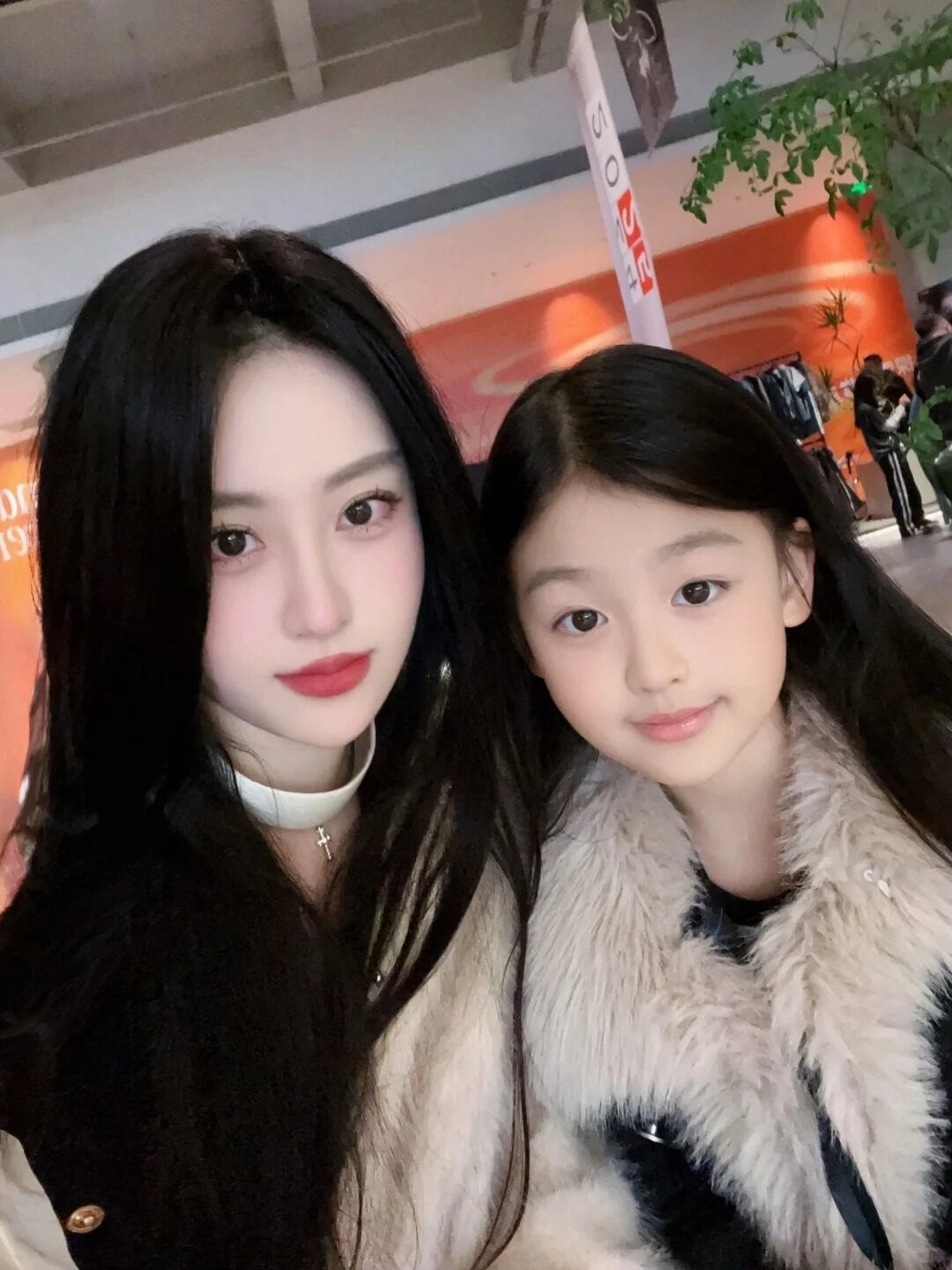 Mẹ và con gái diện áo khoác lông, ánh mắt tràn đầy yêu thương.